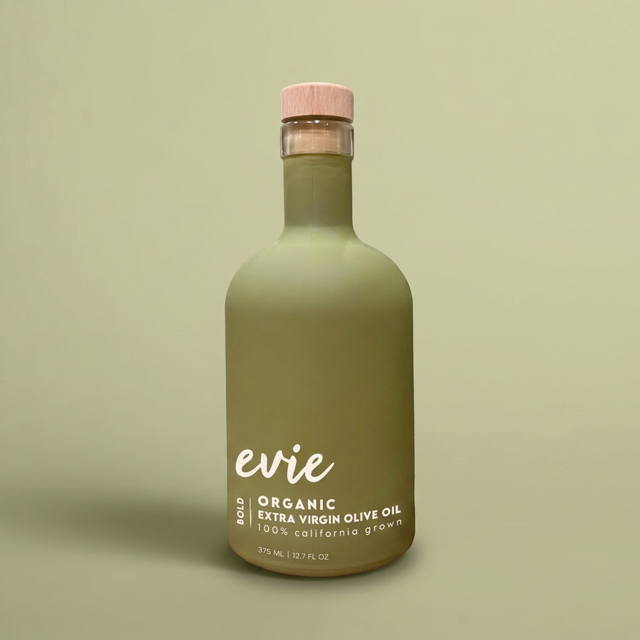 Green bottle of evie organic extra virgin olive oil on a beige background